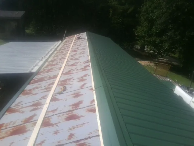 Old rusted panels beside newly installed green metal roofing — Wind Damage Roof Repair by Roofing Brothers in Shreveport