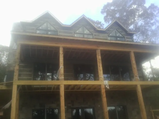 Dormers and porch framing on a large log home under construction — Roof Coating work by our crew in Shreveport