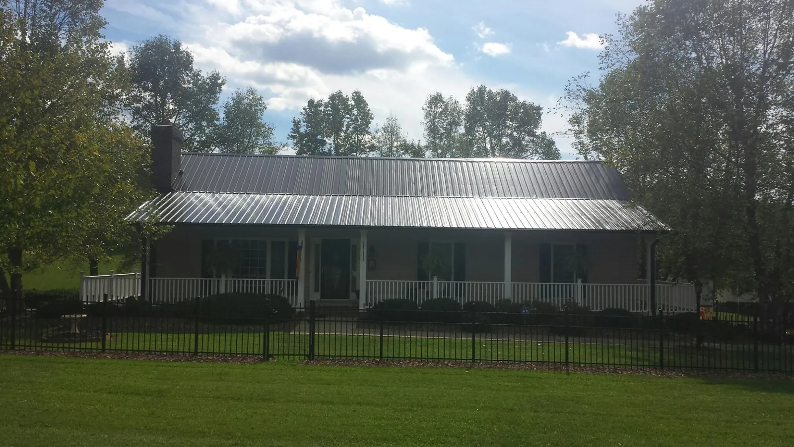 Gray metal roof on a brick ranch with a full width front porch — Gutter Guard Installation work by our crew in Shreveport