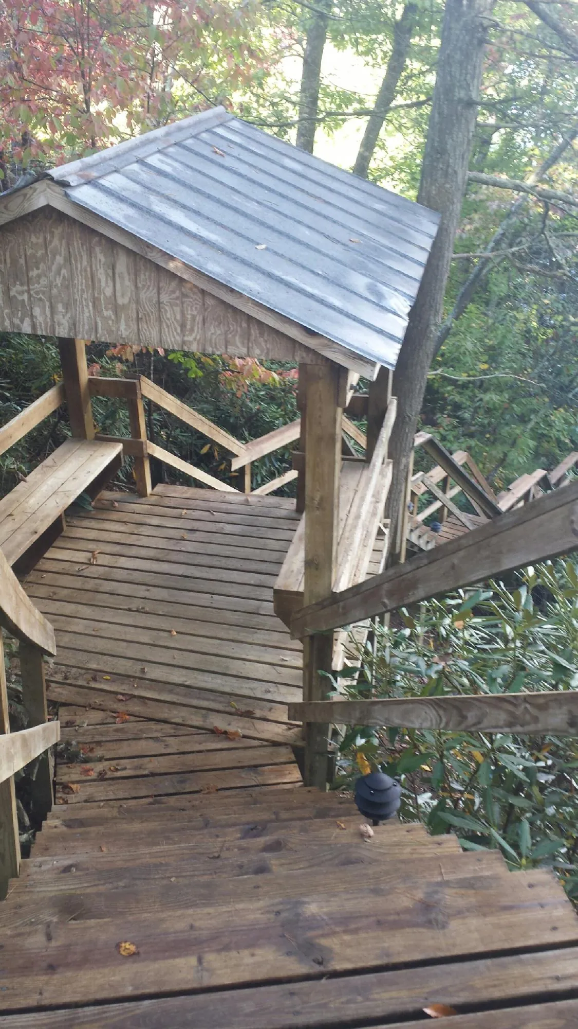 Metal roofed shelter over wooden steps on a wooded walkway — Skylight Repair & Installation work by our crew in Shreveport