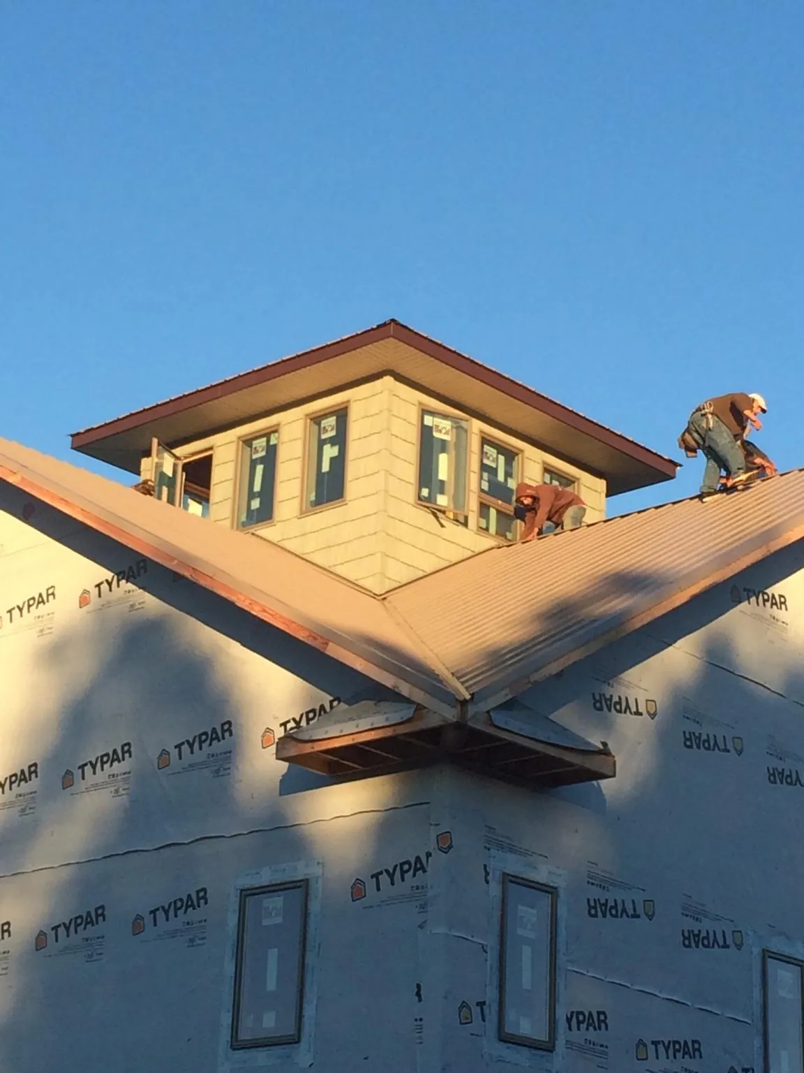Roofers working around a rooftop cupola on a new metal roof at sunset — Roof Waterproofing in Shreveport by Roofing Brothers